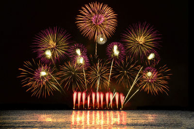 Colorful fireworks celebration from the sea with the midnight sky background.