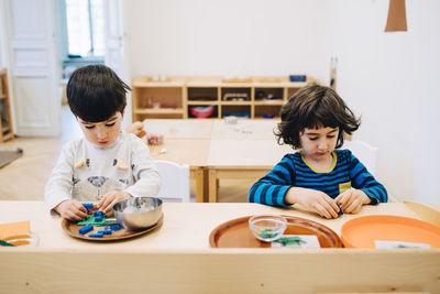 Male students playing with toys at table in child care classroom