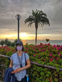 Portrait of young woman standing by sea against sky