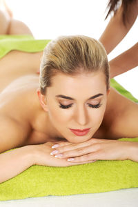 Cropped hands of therapist massaging woman against white background