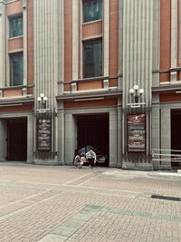 Man on street by footpath against building