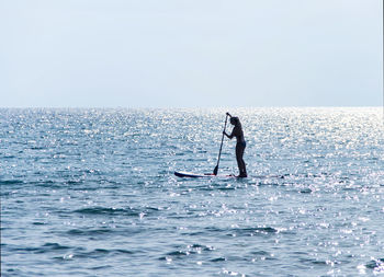 Man surfing on sea against clear sky