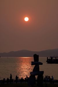 Silhouette people by sea against sky during sunset