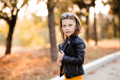 Stylish child girl 5-6 year old wear yellow dress and leather jacket with sun glasses in autumn park