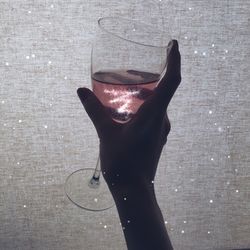 Close-up of hand holding drink against water