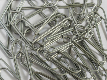 Full frame shot of metallic paper clips on table