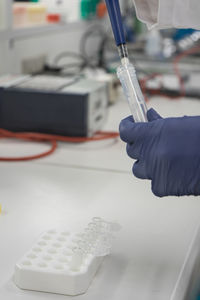 The lab technician performs the experiment by injecting the blue liquid into a test tube