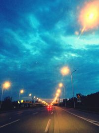 Road passing through illuminated highway at night