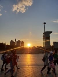 People at commercial dock against sky during sunset