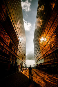 Rear view of person amidst buildings on walkway in city