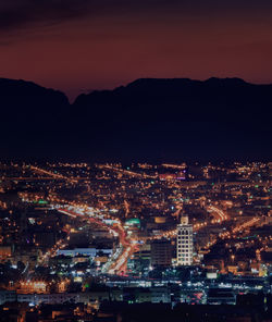 Illuminated cityscape against sky at night