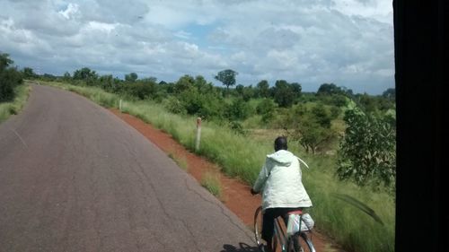 Rear view of man walking on road against sky