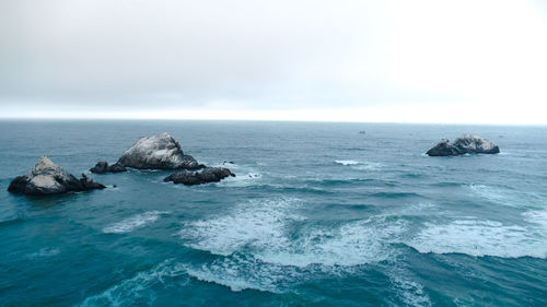 Scenic view of rocks in sea against sky