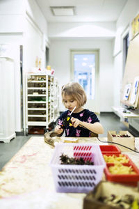 Girl using glue gun at tablet in kindergarten art class