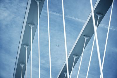 Low angle view of bridge and airplane against sky