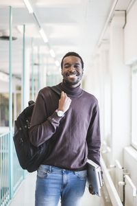 Portrait of smiling male student in corridor of university