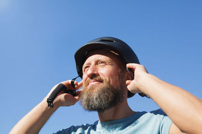 Low angle portrait of man against blue sky