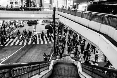 High angle view of people walking on city street over bridge