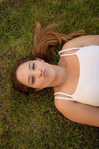Portrait of young woman puckering lips while lying on lawn