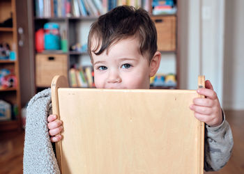 Young boy toddler is playing with his chair and making funny faces