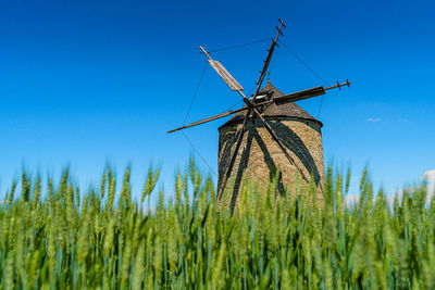 Traditional windmill on field against blue sky