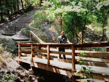 Man standing on footbridge in woods