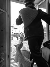 Rear view of man standing by window