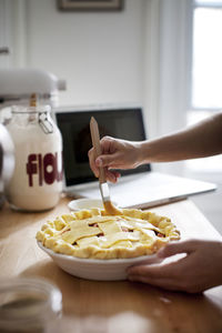 Cropped image of hands brushing egg yolk on pie