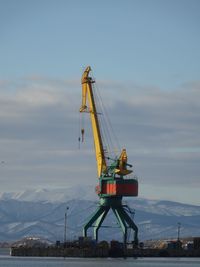 Cranes on pier against sky