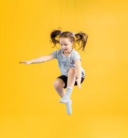 Portrait of young woman exercising against yellow background