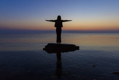 Silhouette person standing by sea against sky during sunset