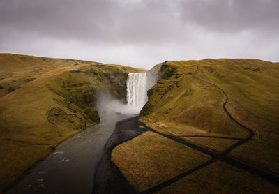 Waterfall with cloudy sky and green grass in iceland