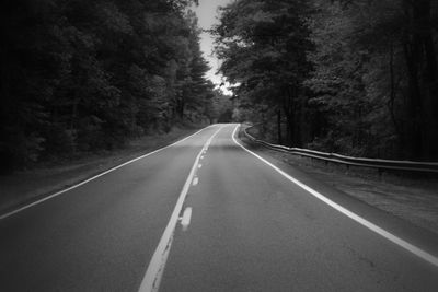 Empty road along trees in forest