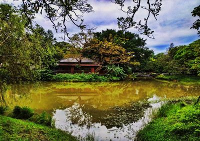 Scenic view of lake by trees and building against sky
