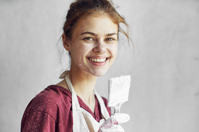 Portrait of smiling young woman standing against wall