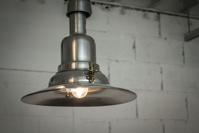 Low angle view of illuminated light bulb hanging on wall