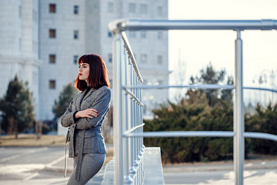 Side view of woman standing against railing