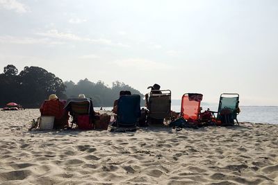 Low angle view of people sitting on sandy beach