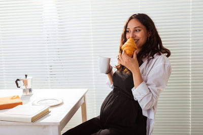 Portrait of young woman sitting on table