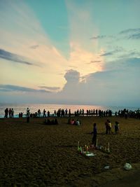 People on beach against sky during sunset