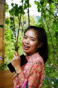 Portrait of a smiling young woman holding plant