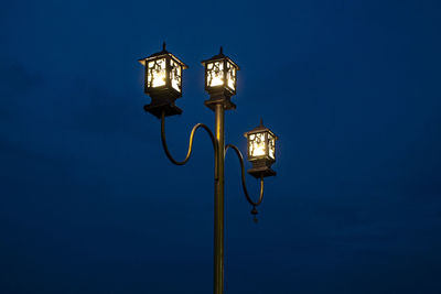 Low angle view of illuminated street light against blue sky