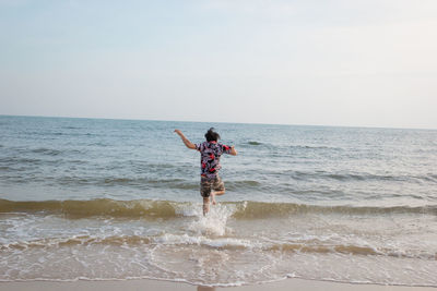 Rear view of man on beach against sky