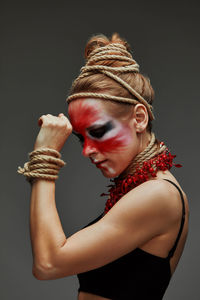 Side view of young woman drinking water against black background