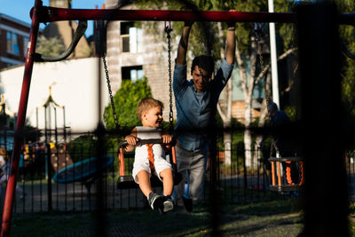 Girl with man swinging in playground