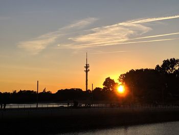 Silhouette communications tower against sky during sunset