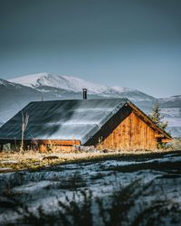 Houses by snowcapped mountain against sky during winter