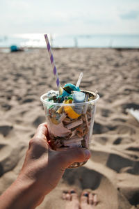 Midsection of person holding ice cream on beach