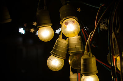 Low angle view of illuminated light bulb hanging from ceiling