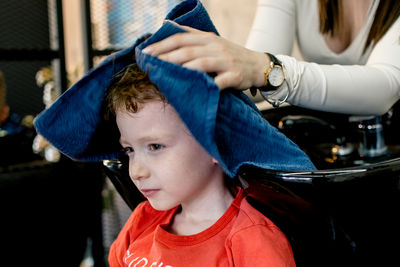 A little blond boy gets his hair washed at a barber shop.